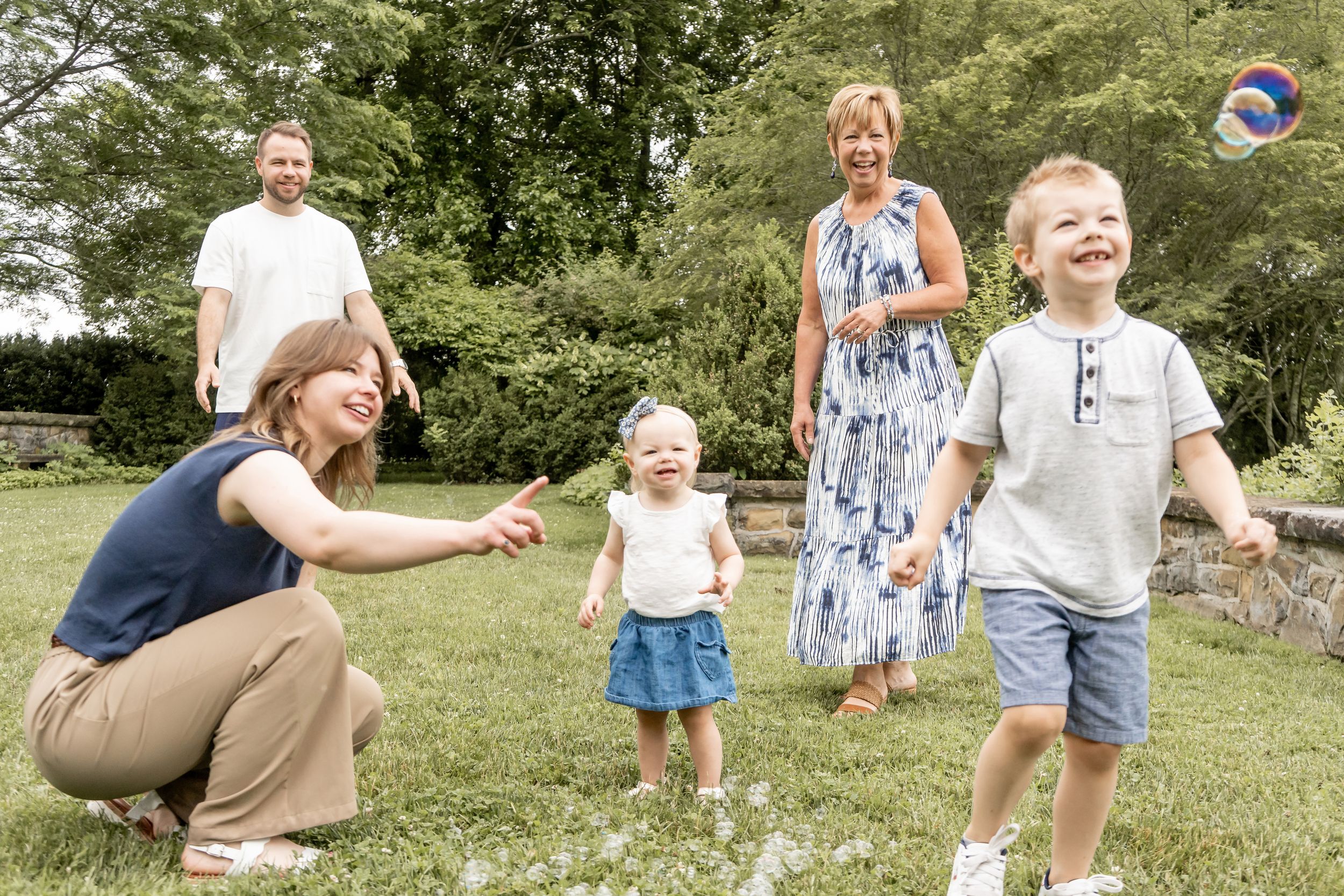 Family playing with a ball outdoors on green grass, children laughing with parents and grandparents.