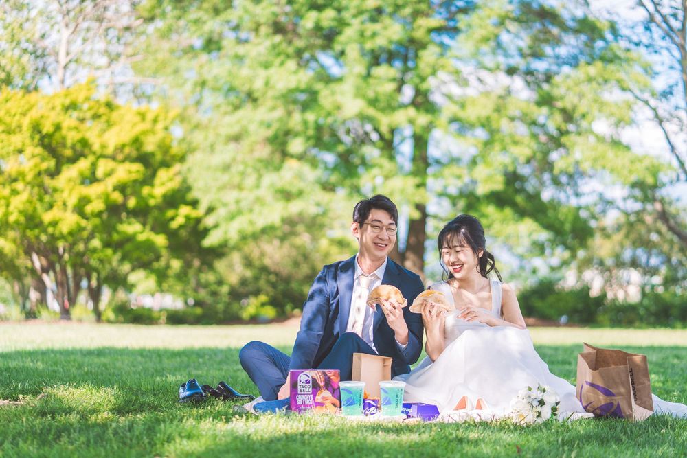 A group of friends relaxing and having a picnic on green grass in a sunny park.