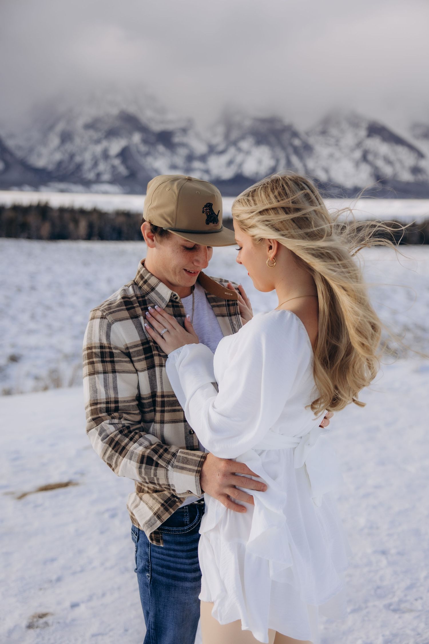A romantic winter engagement photo with snow-capped mountains in Grand Teton National Park.