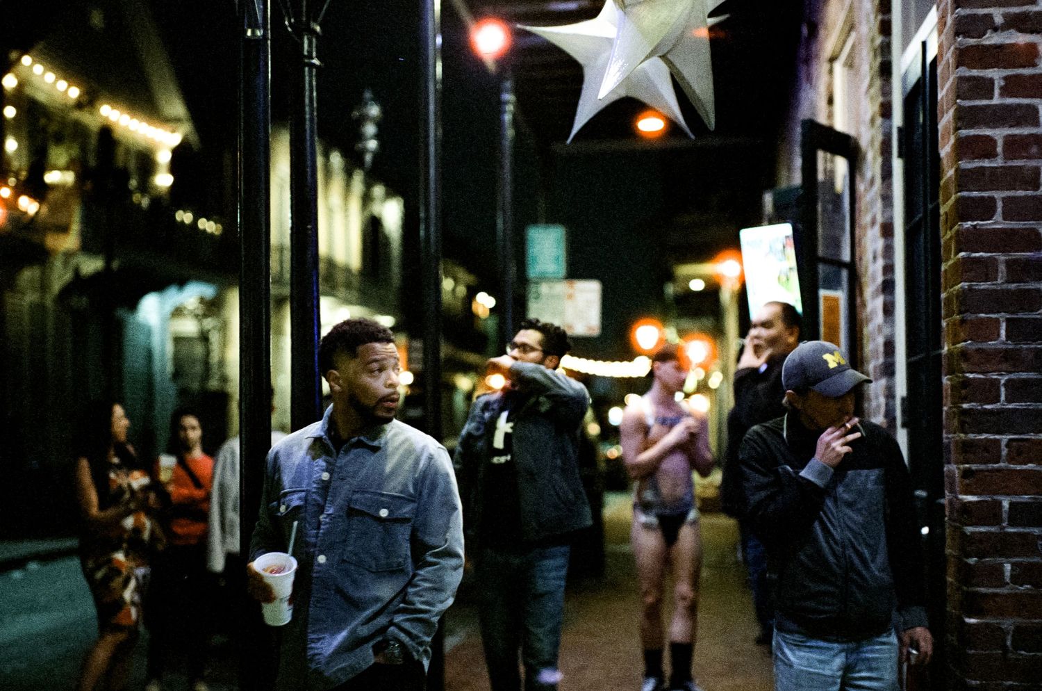 People gathered outside on a city street at night under decorative star lights.
