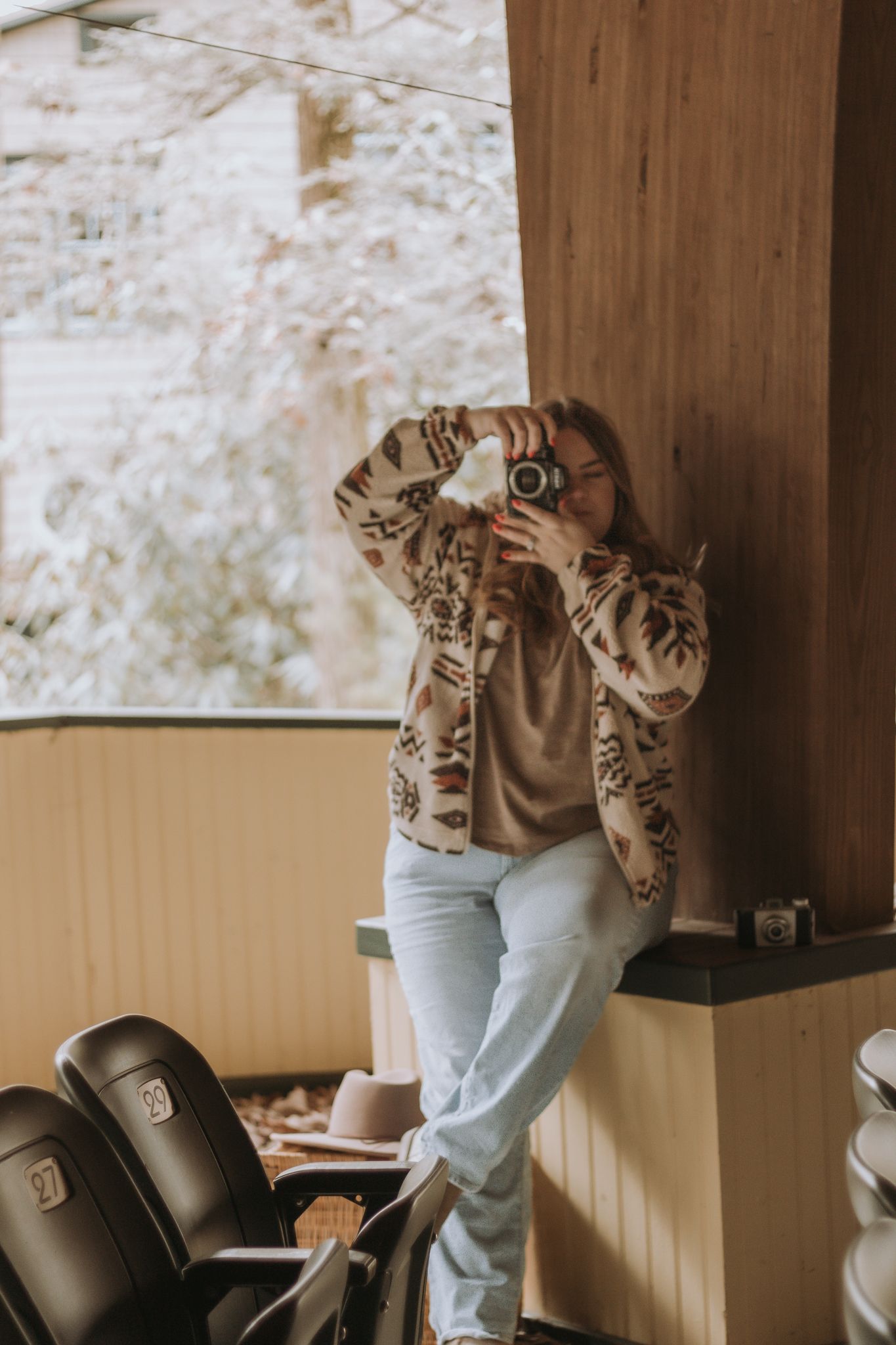 A sequence of four images showing someone in a tiger print top and light jeans leaning against a wooden wall.