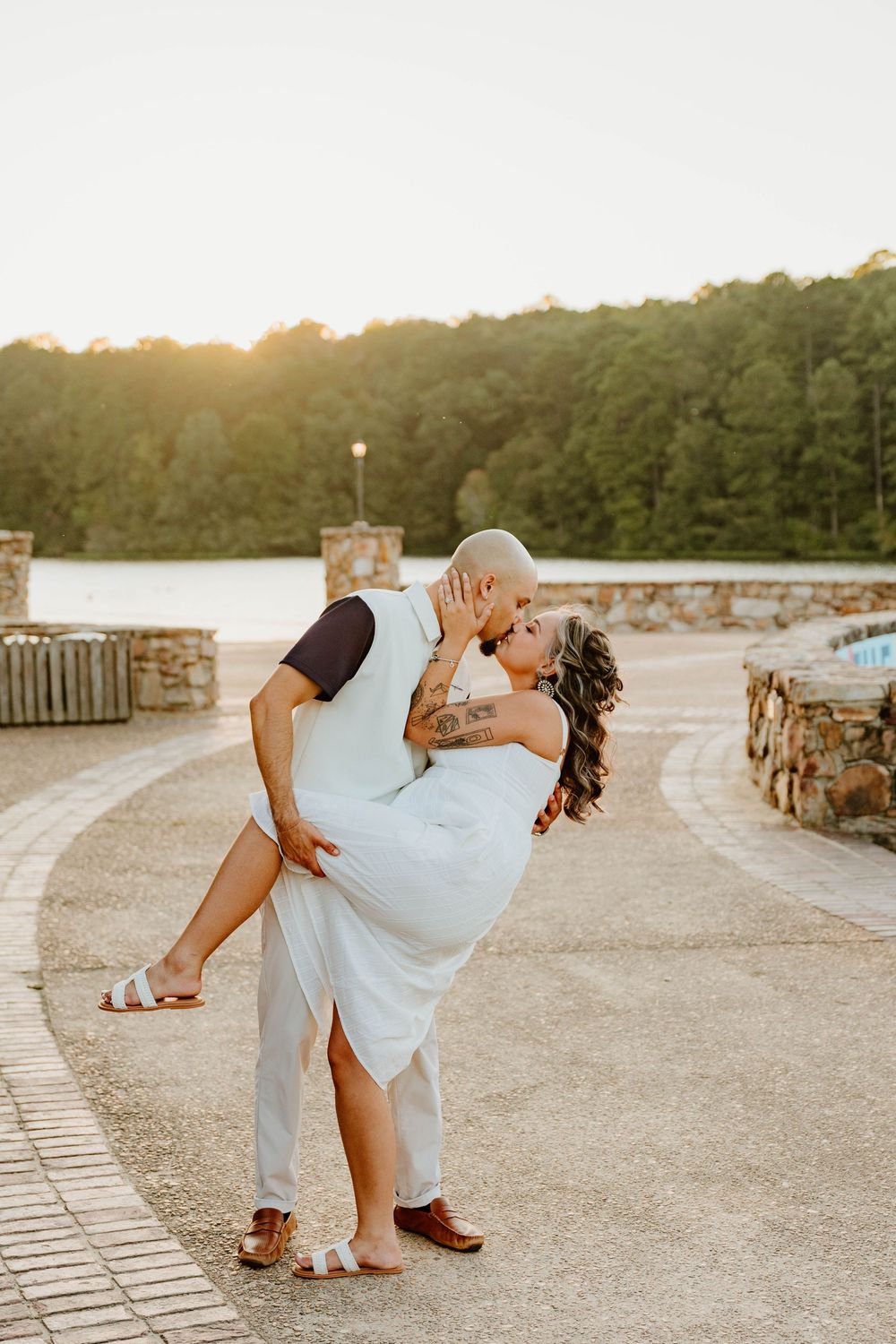 Couple in white attire dancing and dipping during a romantic sunset photoshoot.