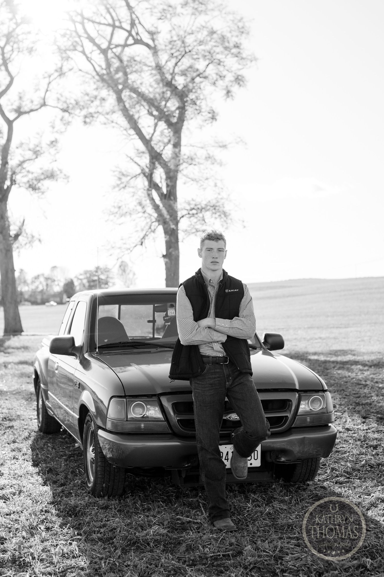 A black and white portrait of an athlete leaning against a Ford Ranger pickup truck.