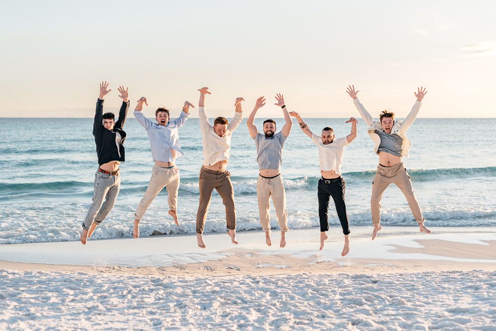 Brothers playing and jumping for a photo during sunset time with white sandy beach and beautiful sunset ocean background