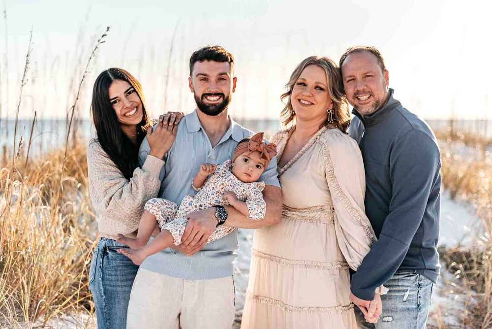 Generational Family photo of grandparents, kids, and new born daughter framed on the stunning beach with sand dunes and sea oats