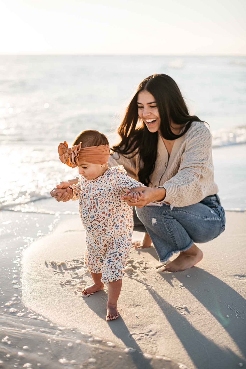 Mother teaching her daughter how to walk along the beach at sunset in Miramar Florida with photographer
