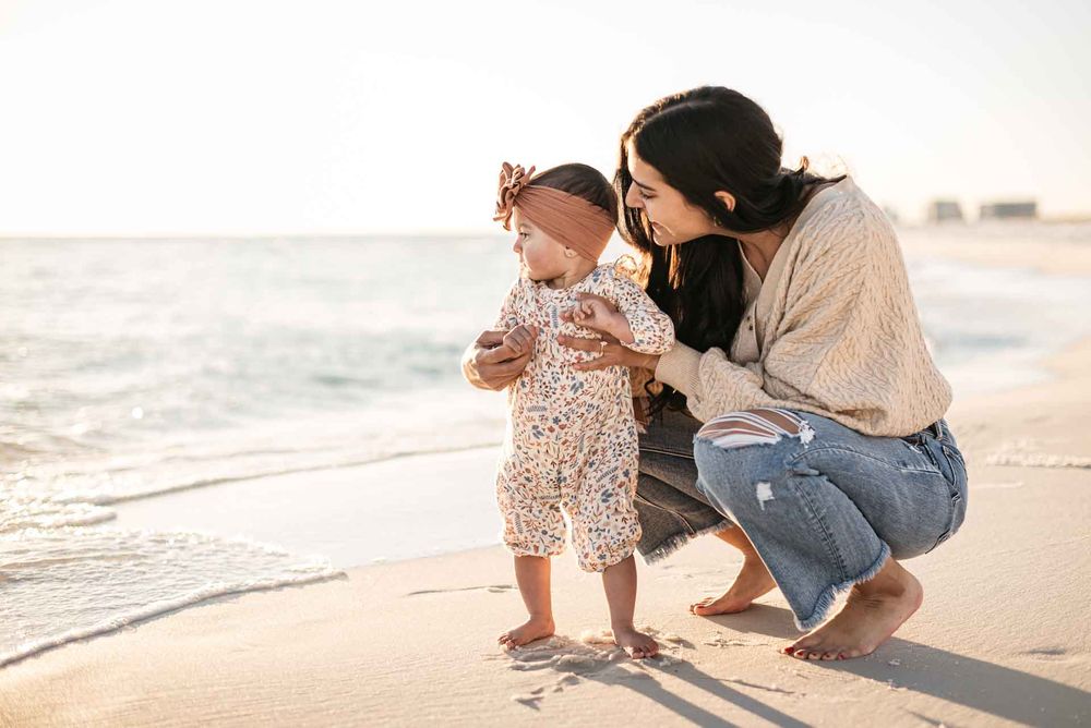 Mother showing her daughter the Gulf of Mexico ocean during sunset with a photographer in Destin Florida