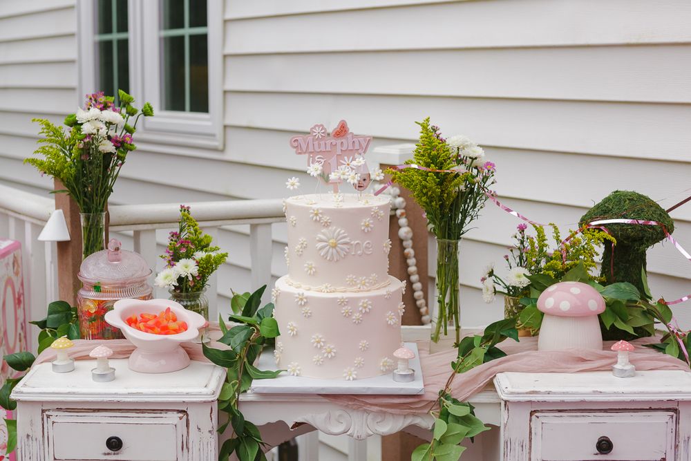 Cake table setup featuring pink mushrooms and fairy-themed decor, photographed by NYC family photographer Paula Ortiz