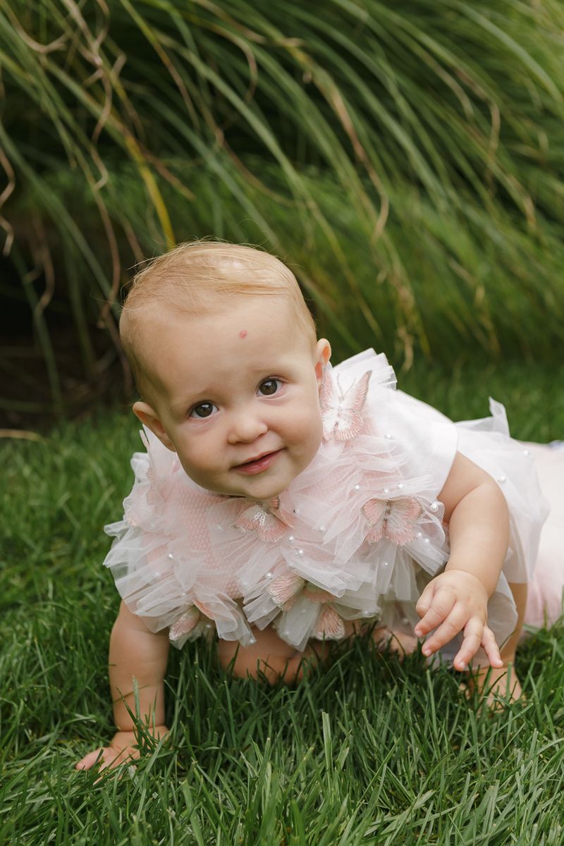 Candid shot of the birthday girl crawling towards the camera, by NYC family photographer Paula Ortiz