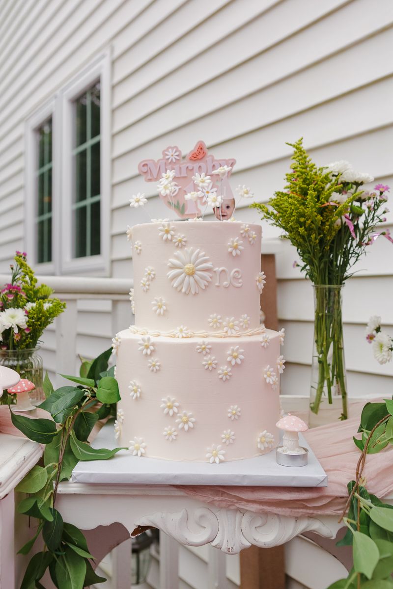 Soft pink birthday cake adorned with small daisies, captured by NYC family photographer Paula Ortiz