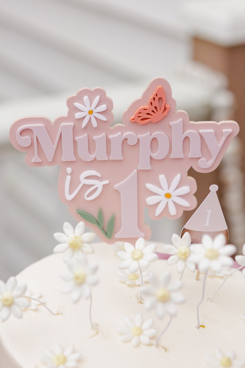 Detail of a pink party topper with the birthday girl's name and number 1, captured by NYC family photographer Paula O