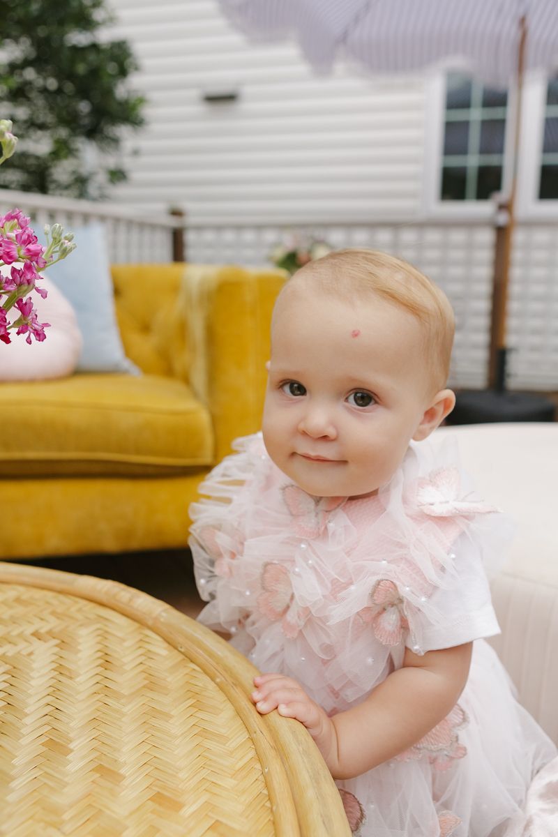 Birthday girl standing up and exploring her surroundings, photographed by NYC family photographer Paula Ortiz