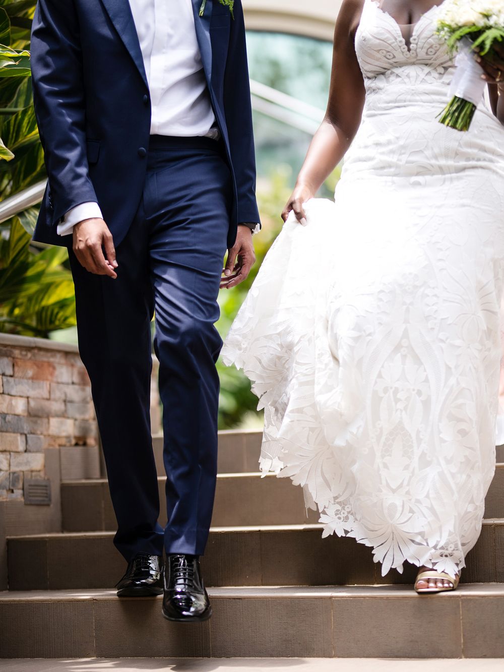 Close-up of bride and groom's formal attire as they stand on stone steps.