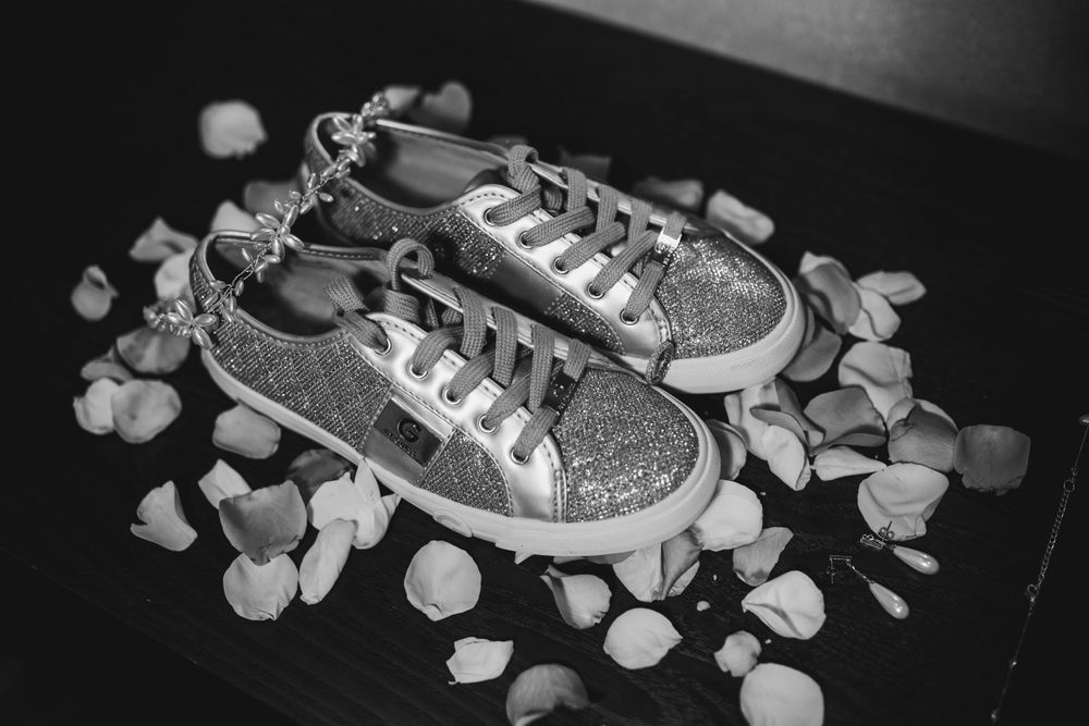 Sparkly silver sneakers surrounded by scattered rose petals.