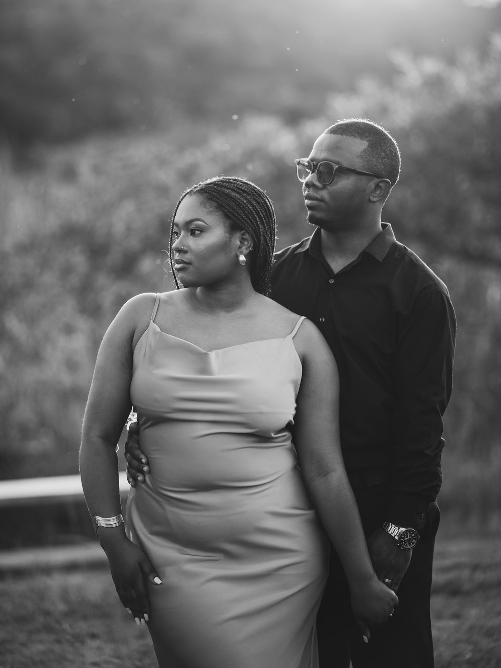 Artistic black and white portrait of couple against moody sky backdrop.