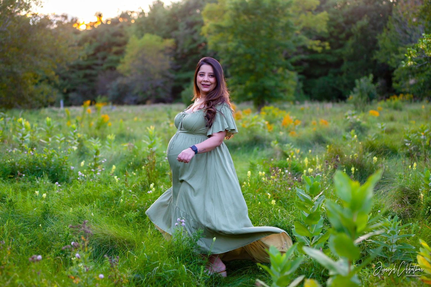 Photo of an expecting mother outdoors at sunset, capturing a serene and glowing moment with warm, golden light.