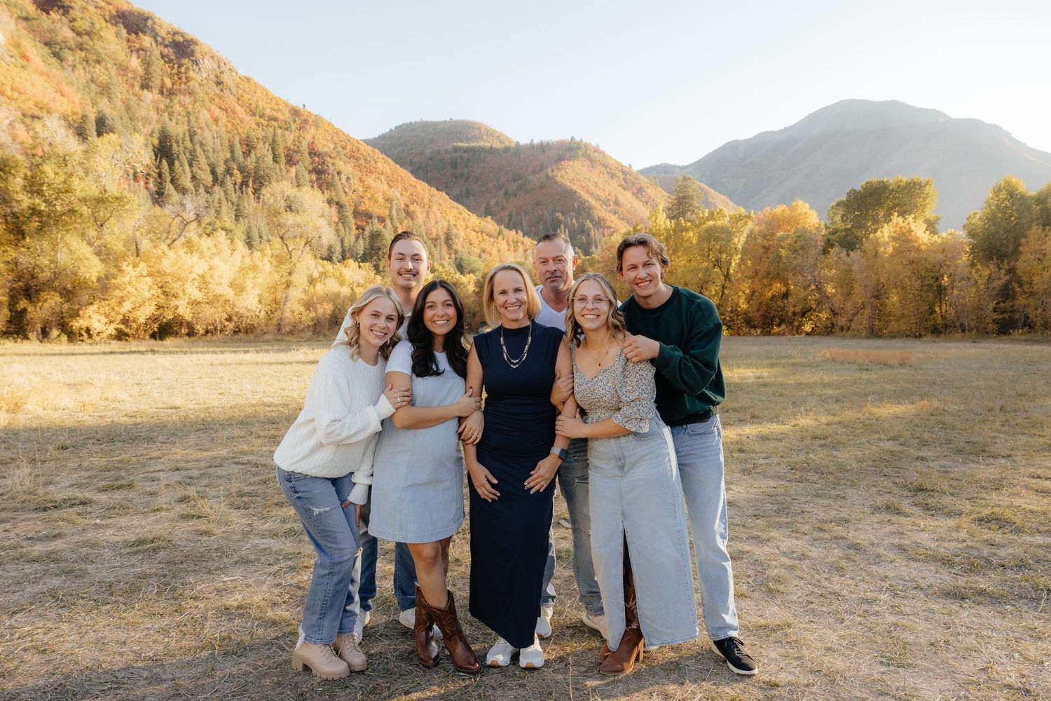 A joyful extended family poses together in a golden autumn mountain meadow for a fall portrait.