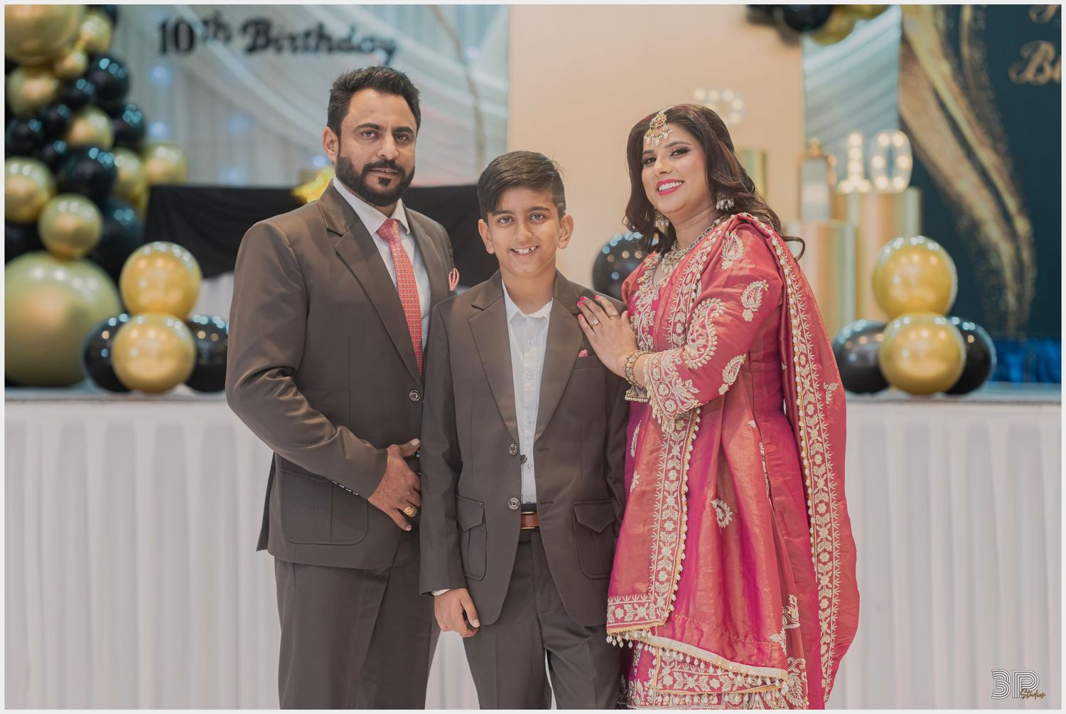 Family of three posing together in a professional studio, with soft lighting highlighting their warm smiles and close bond