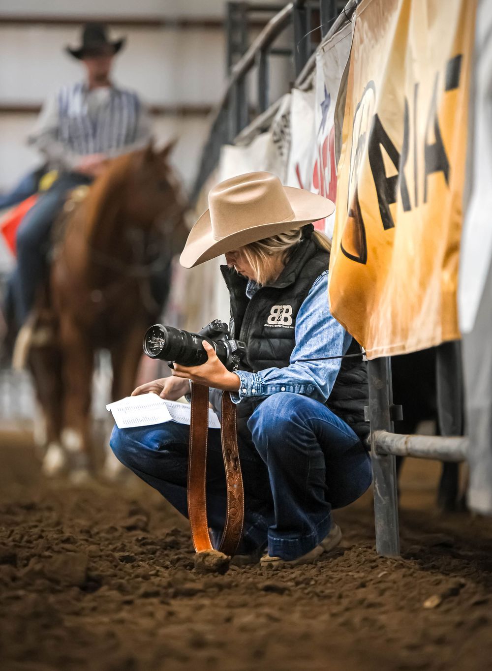Close-up of western boots and jeans in a dusty rodeo arena.