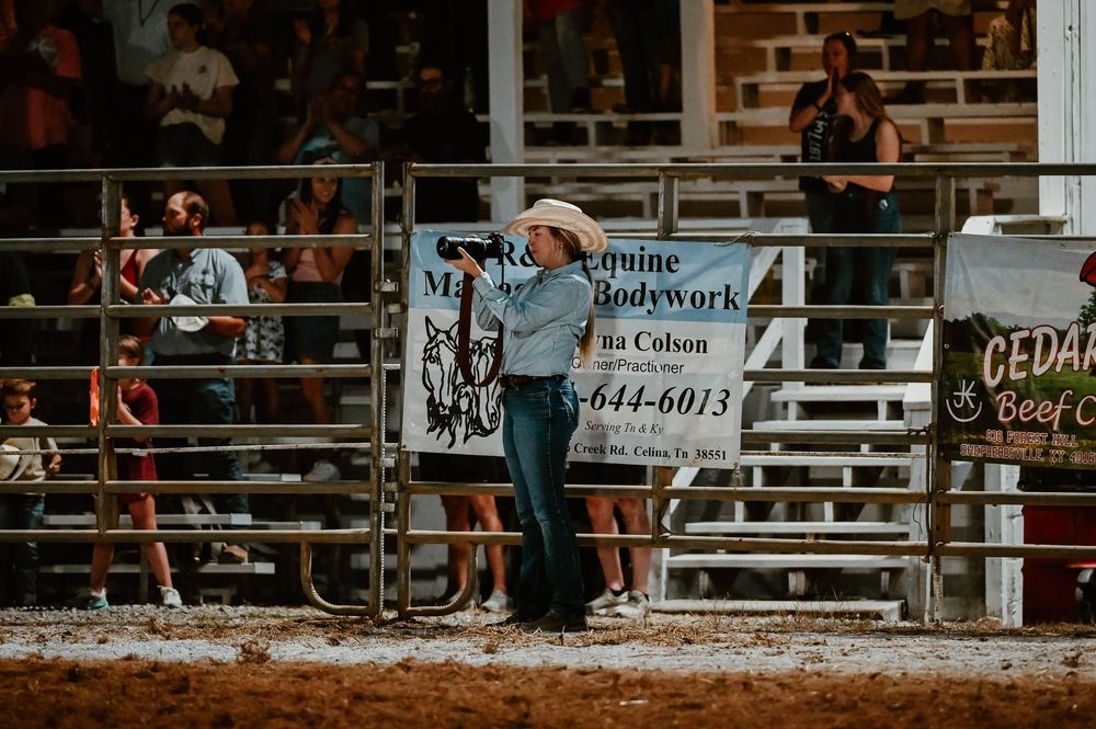 Spectators watching a rodeo event from bleachers with advertising banners visible.