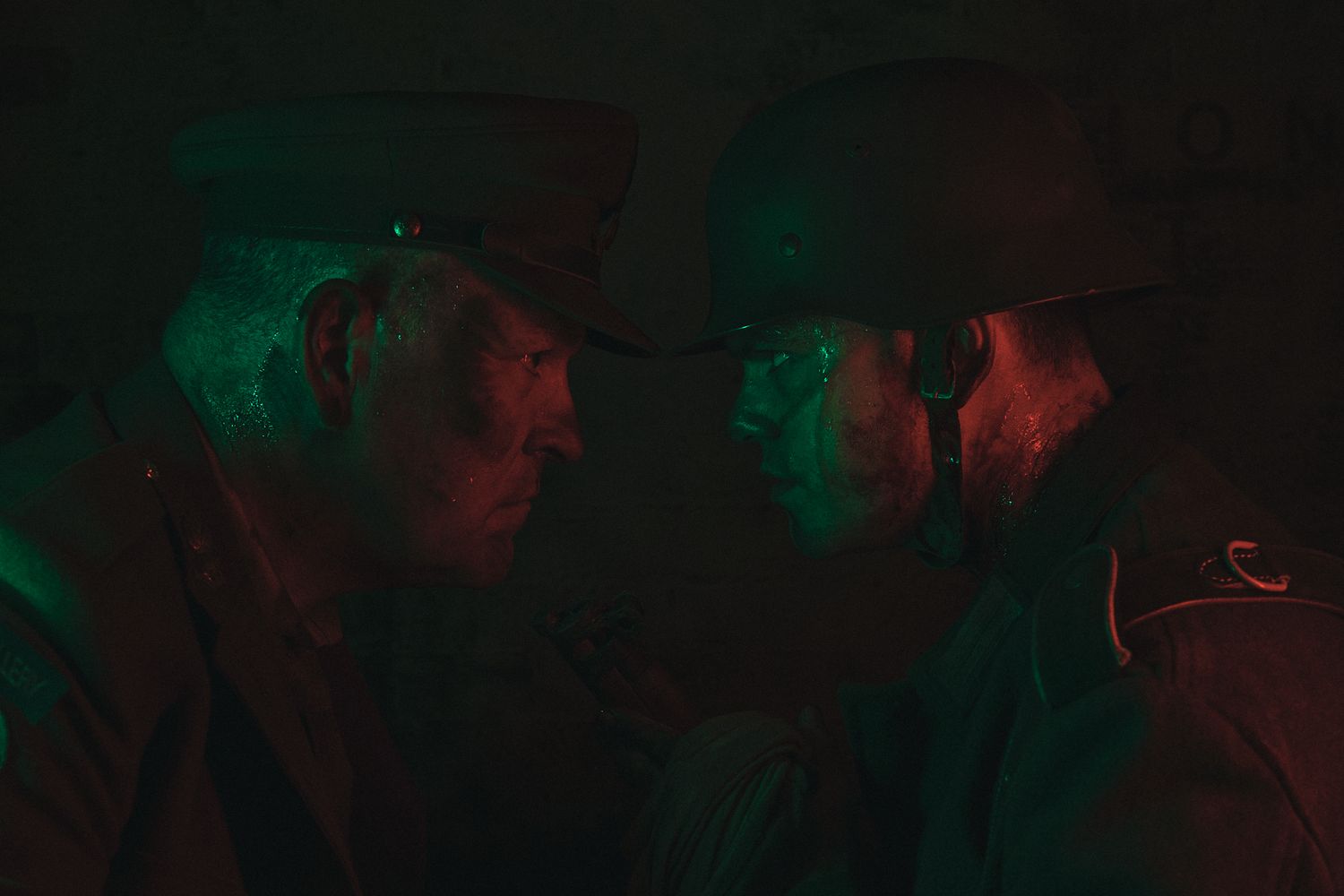 Two male models in military uniforms facing off under dramatic lighting, creating intense, cinematic mood