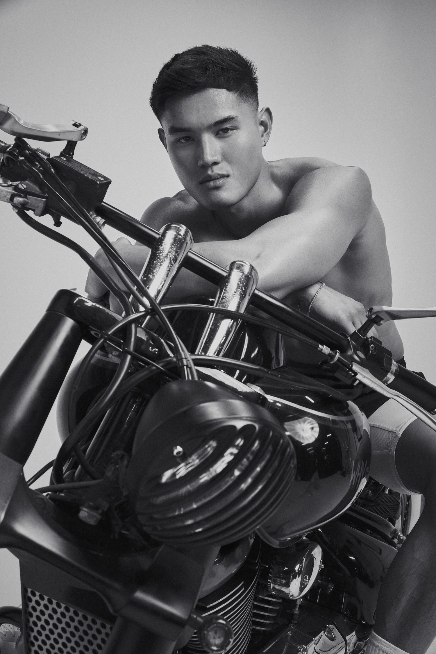 Male model on motorcycle, black and white portrait, exuding intensity and focus with direct eye contact