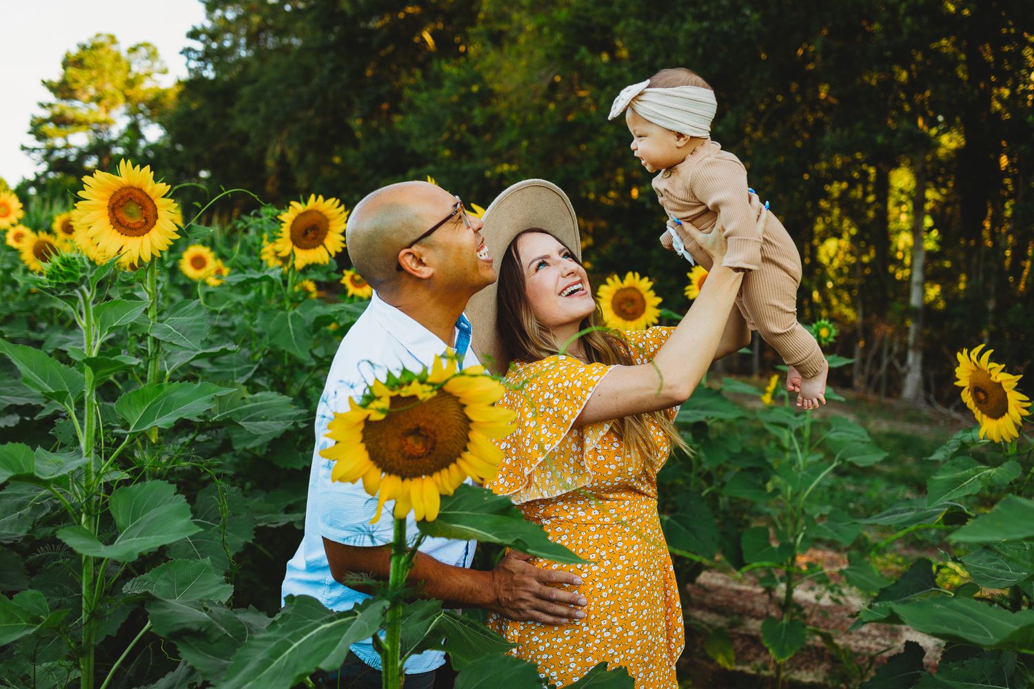 A family enjoys a joyful moment together in a vibrant sunflower field during golden hour.