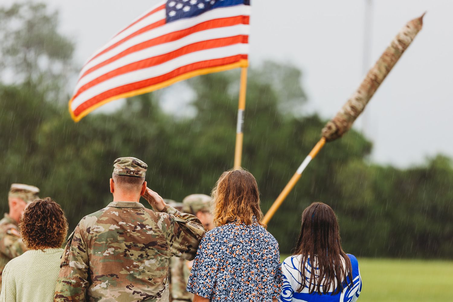 American flags wave during military ceremony on grassy field.