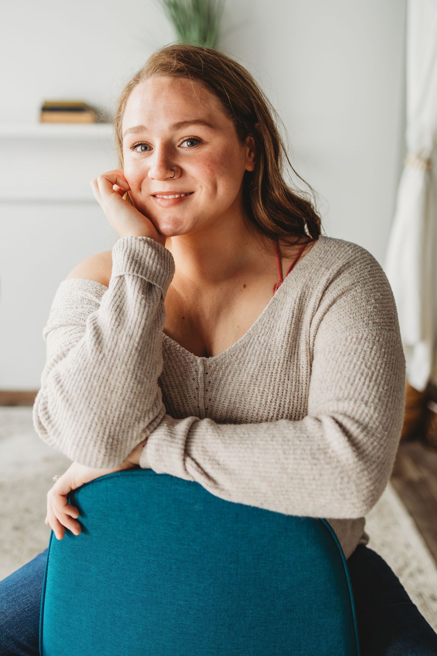 Casual lifestyle portrait of woman relaxing on teal couch in natural light.