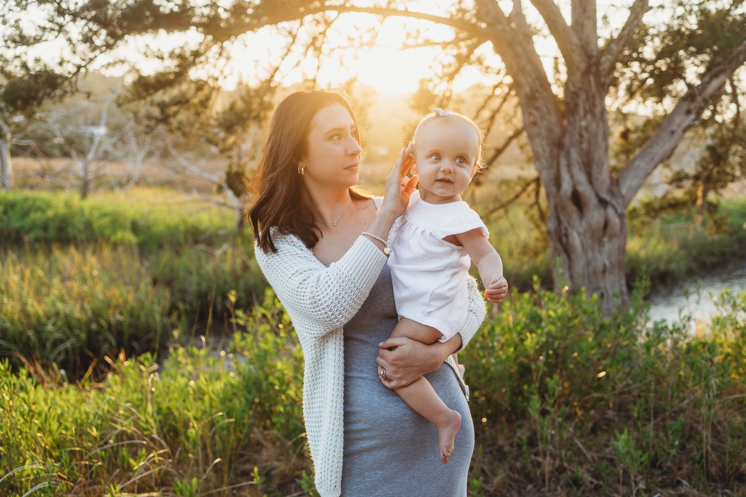 Mother and child embracing during sunset photoshoot in natural outdoor setting.