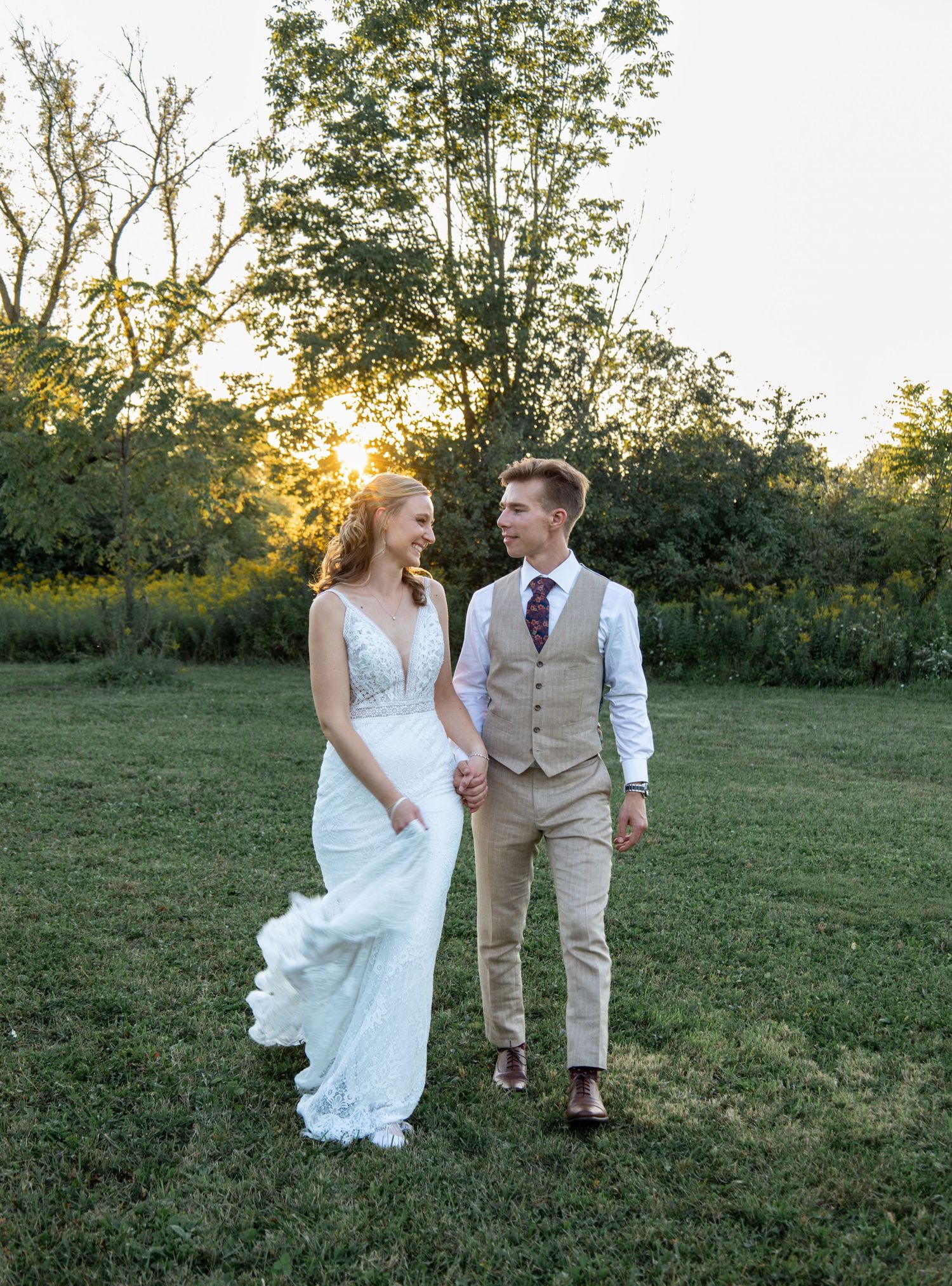 candid picture of bride and groom walking in sunset