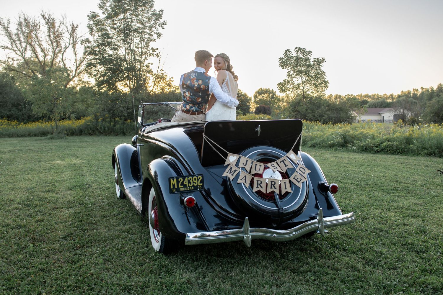Editorial photo of bride and groom on vintage car with just married sign