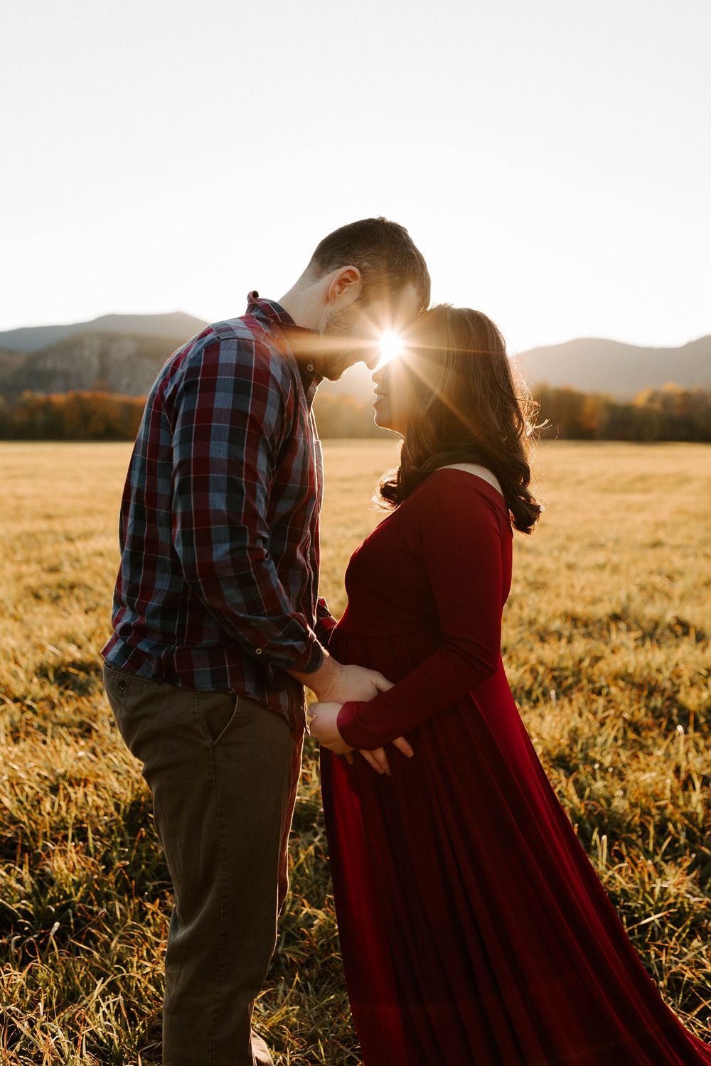 An outdoor couple photographed for a maternity photoshoot during golden hour.
