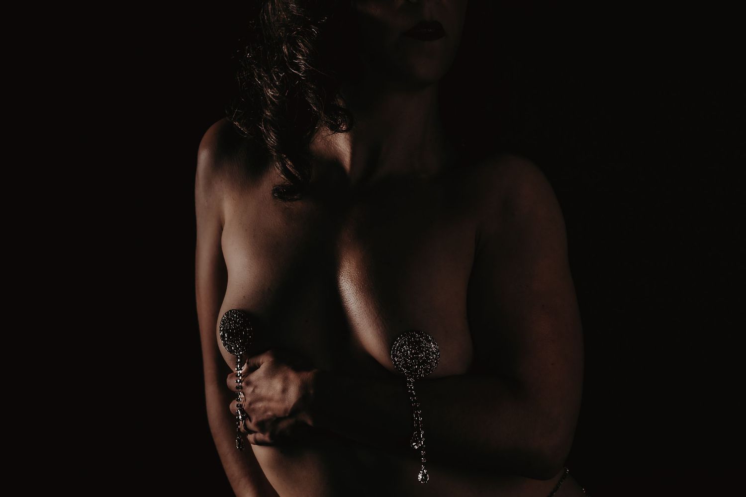 Artistic nude silhouette poses in dramatic lighting against a dark background create a sensual composition.