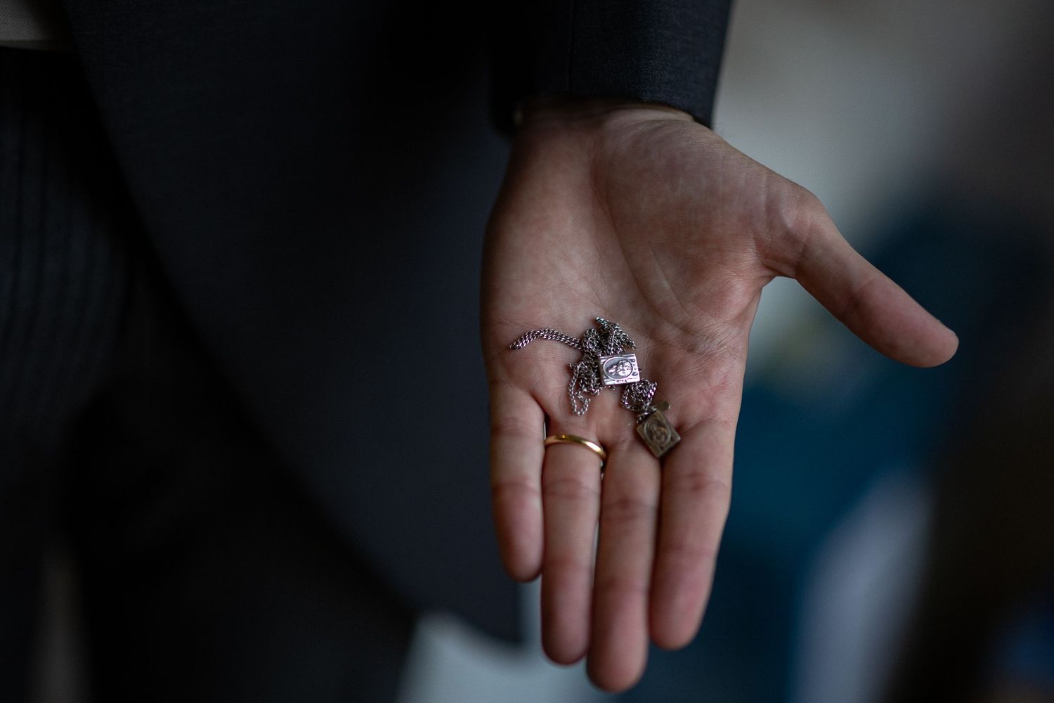 Open palm of a person in business attire holding small metal keys in natural light.