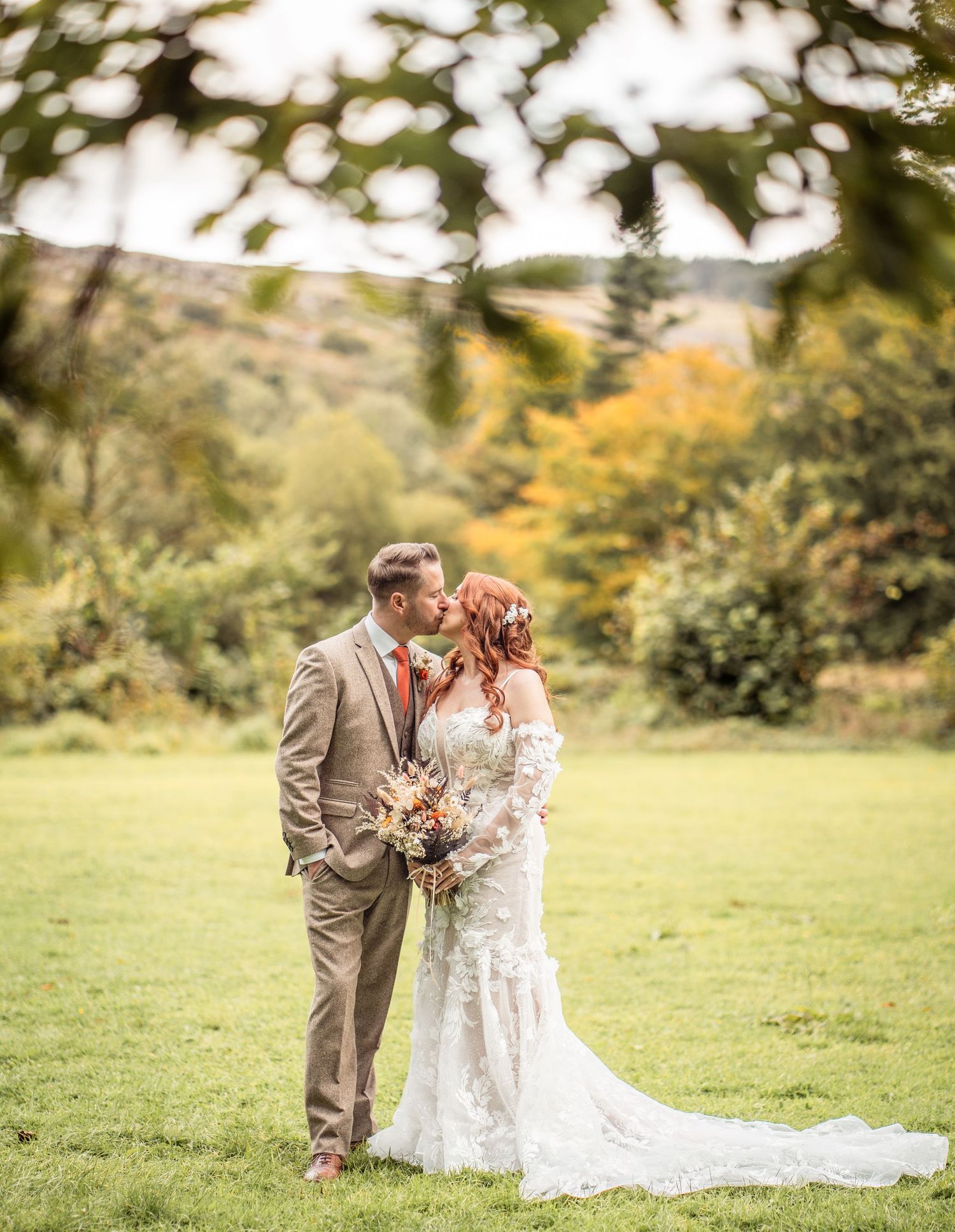 A couple shares a romantic moment in a lush outdoor garden setting during their autumn wedding celebration.