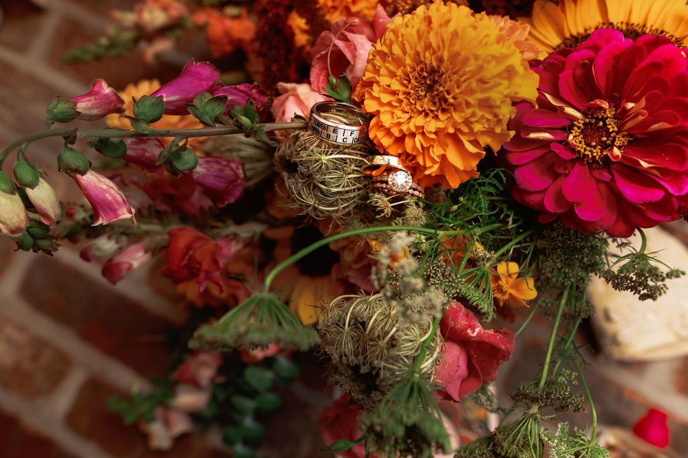 Vibrant autumn floral arrangement with orange marigolds, red dahlias, and pink blooms in rustic fall table decor.