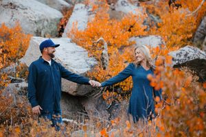 Couple explores outdoor setting with vibrant orange autumn foliage.