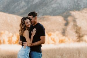 Couple shares tender moment against mountain backdrop during golden hour.