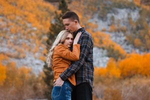 Couple shares romantic moment surrounded by bright autumn colors in mountain setting.