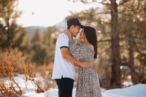 Couple shares intimate moment in snowy mountain setting during sunset.