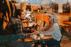 Couple enjoys coffee date in cozy cafe with warm lighting.