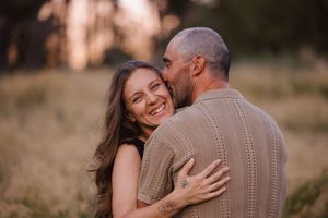 Romantic couple sharing intimate moment outdoors during sunset photoshoot.