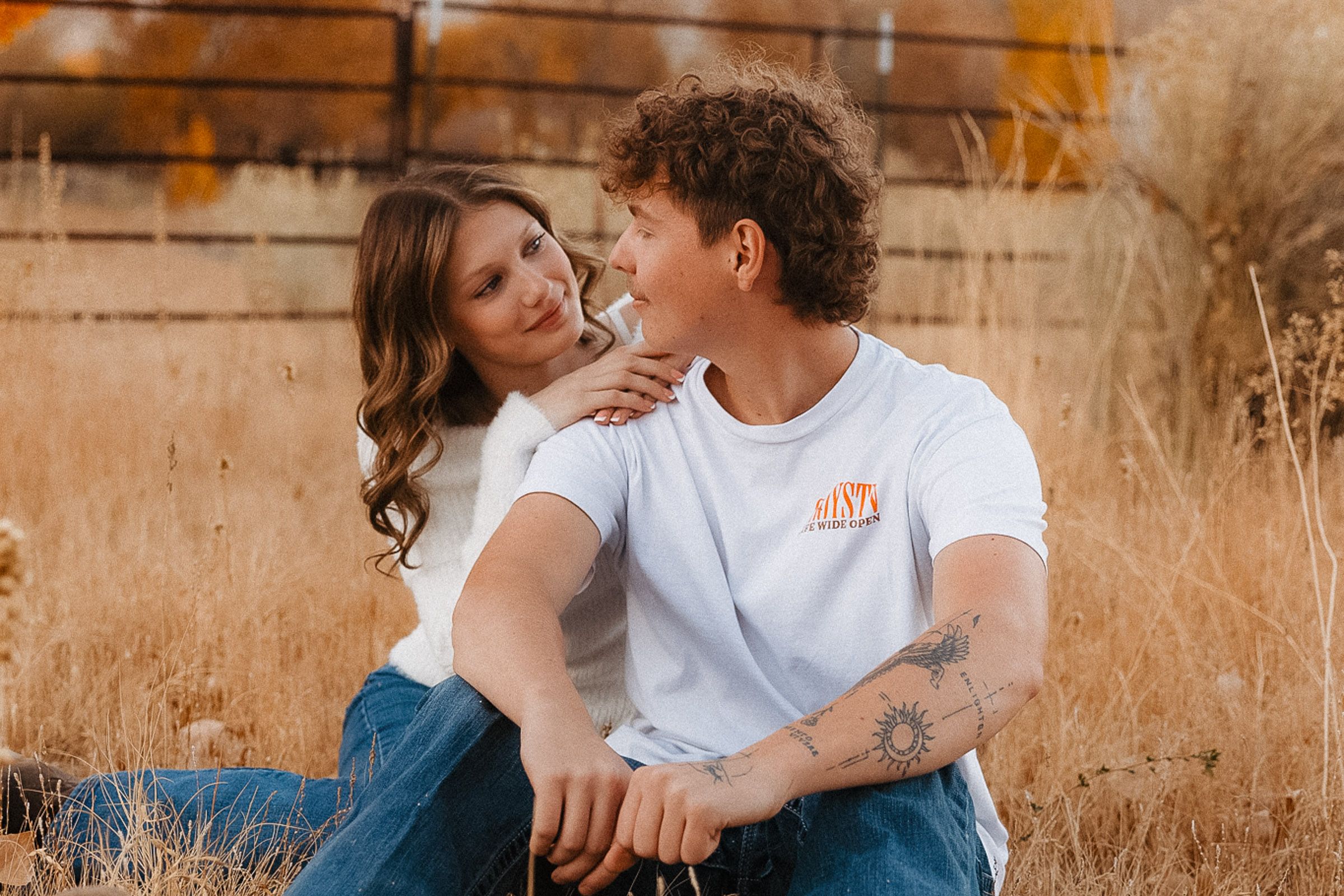 Candid moment between couple lounging on rustic wooden structure.