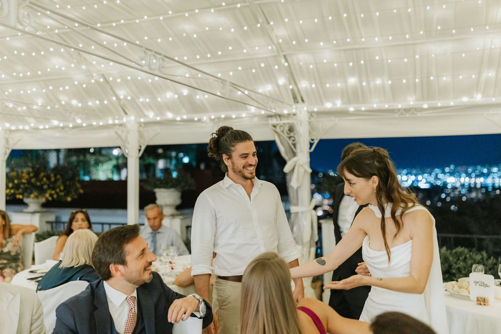 Wedding guests dancing and celebrating under twinkling string lights at an outdoor evening reception.