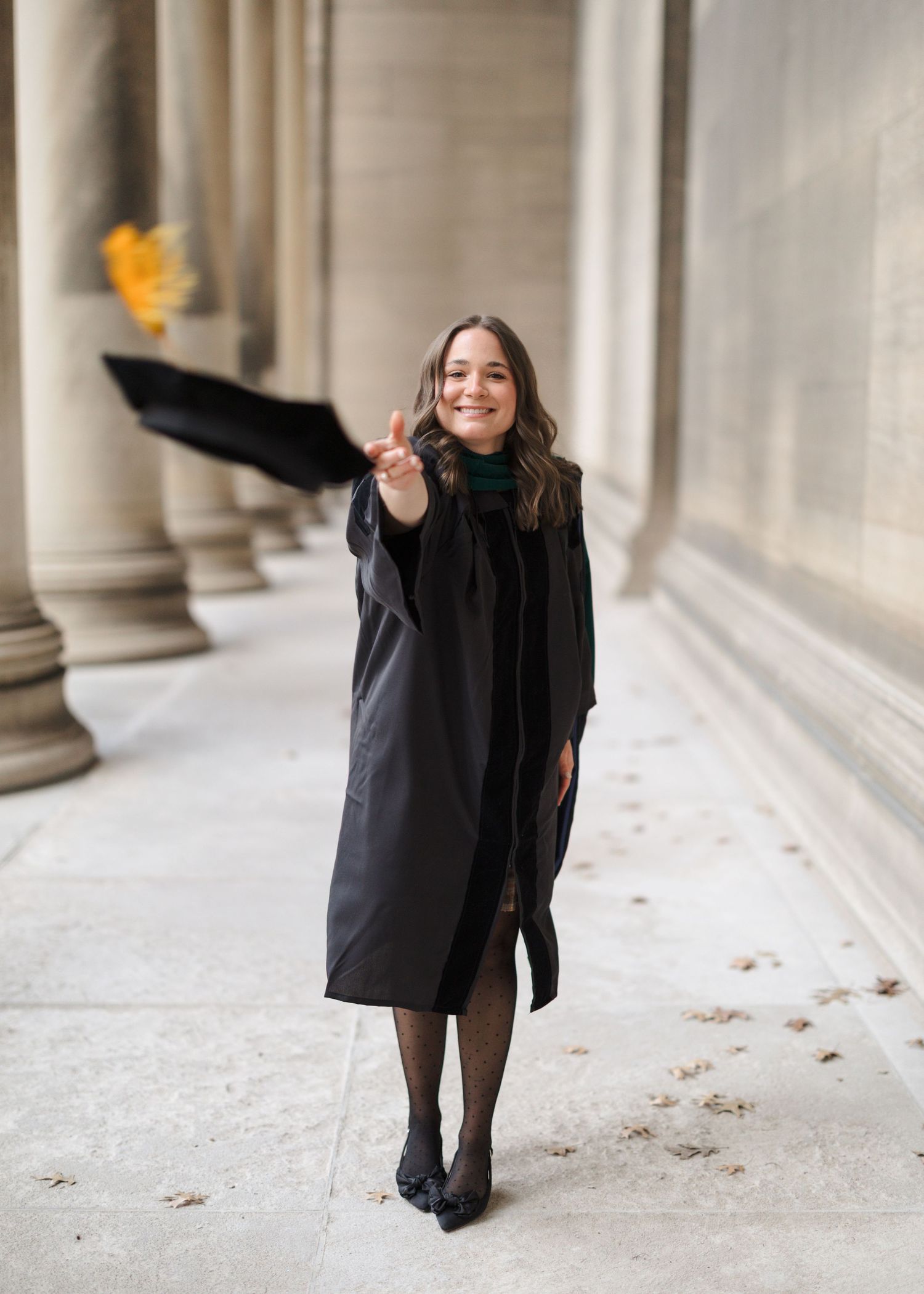 A sequence of five photos showing a person in black clothing walking and twirling along a columned hallway.