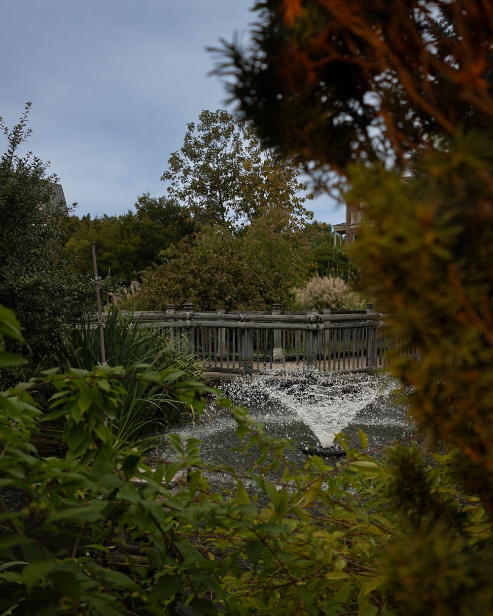 Stone fountain surrounded by lush greenery in a garden landscape.