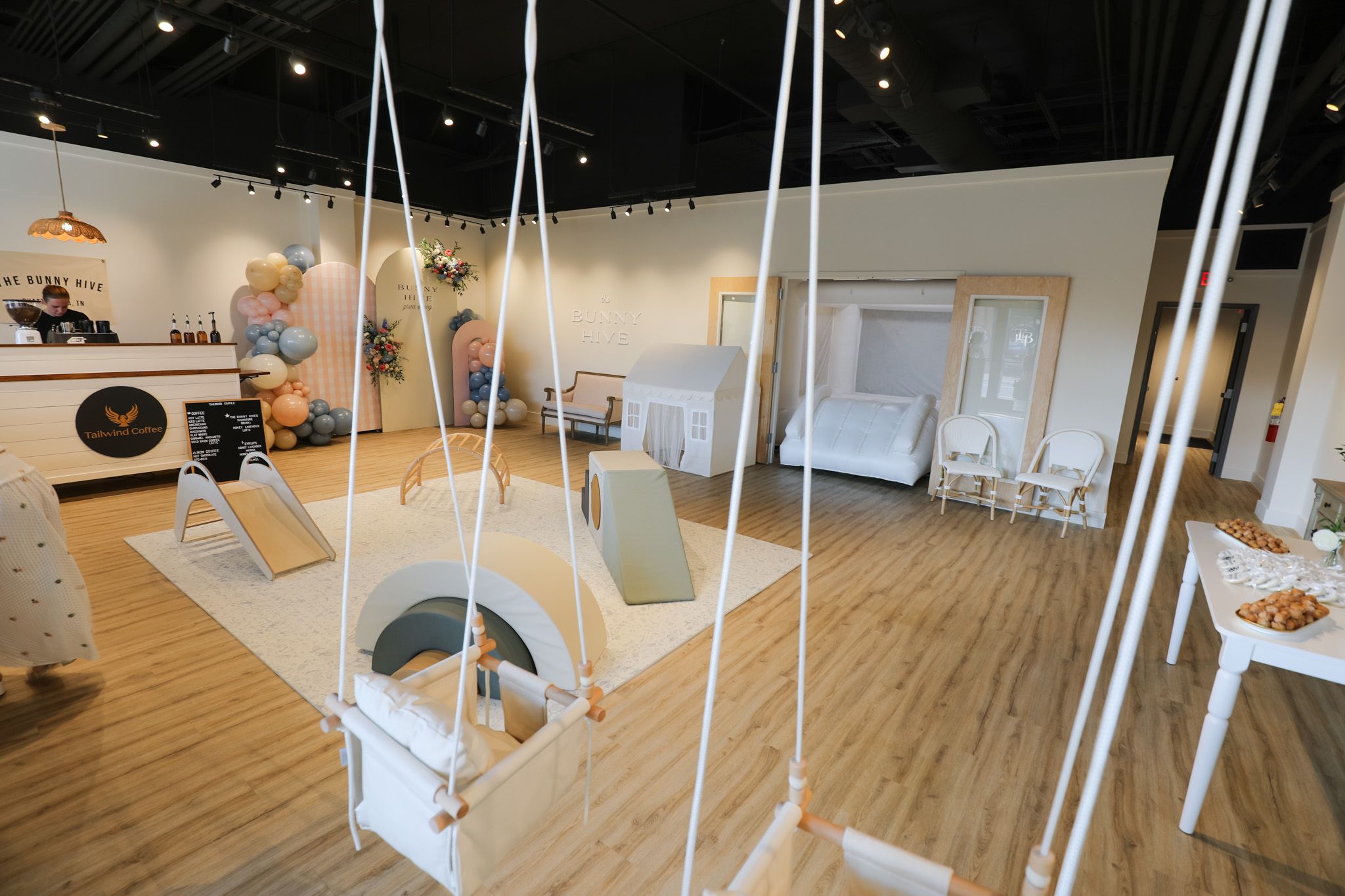 Interior view of a minimalist art gallery space with white walls, hardwood floors, and hanging installations.