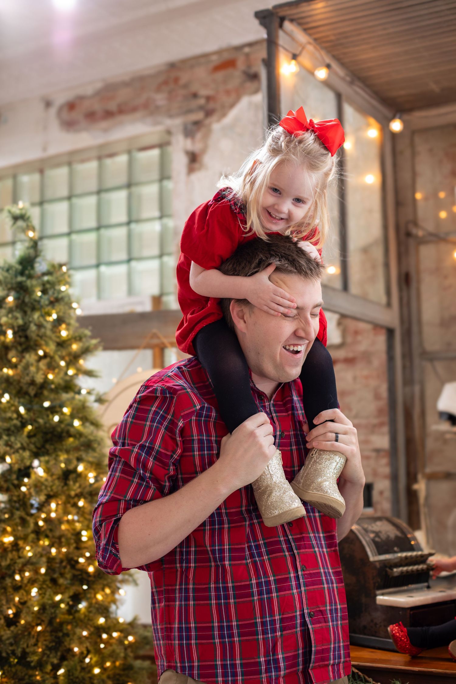 Candid Cincinnati family portrait of a daughter sitting on her dad’s shoulders during a fun Christmas photo session.