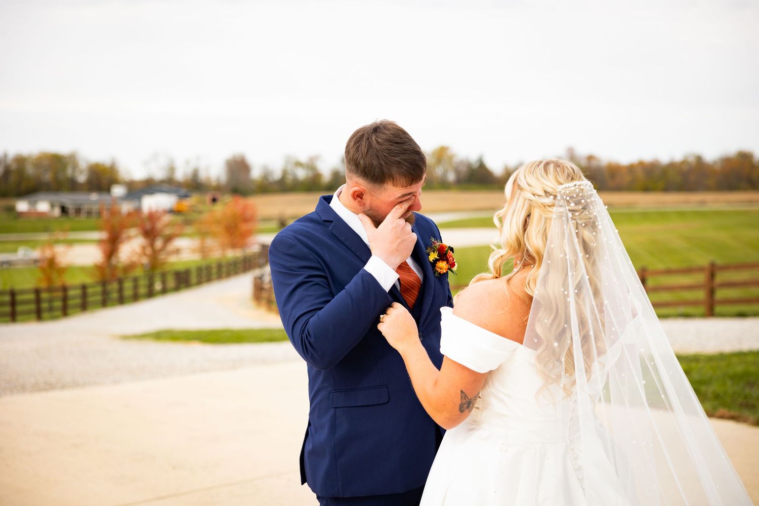 A romantic wedding couple shares tender moments in a rustic countryside setting with wooden fences and autumn fields.